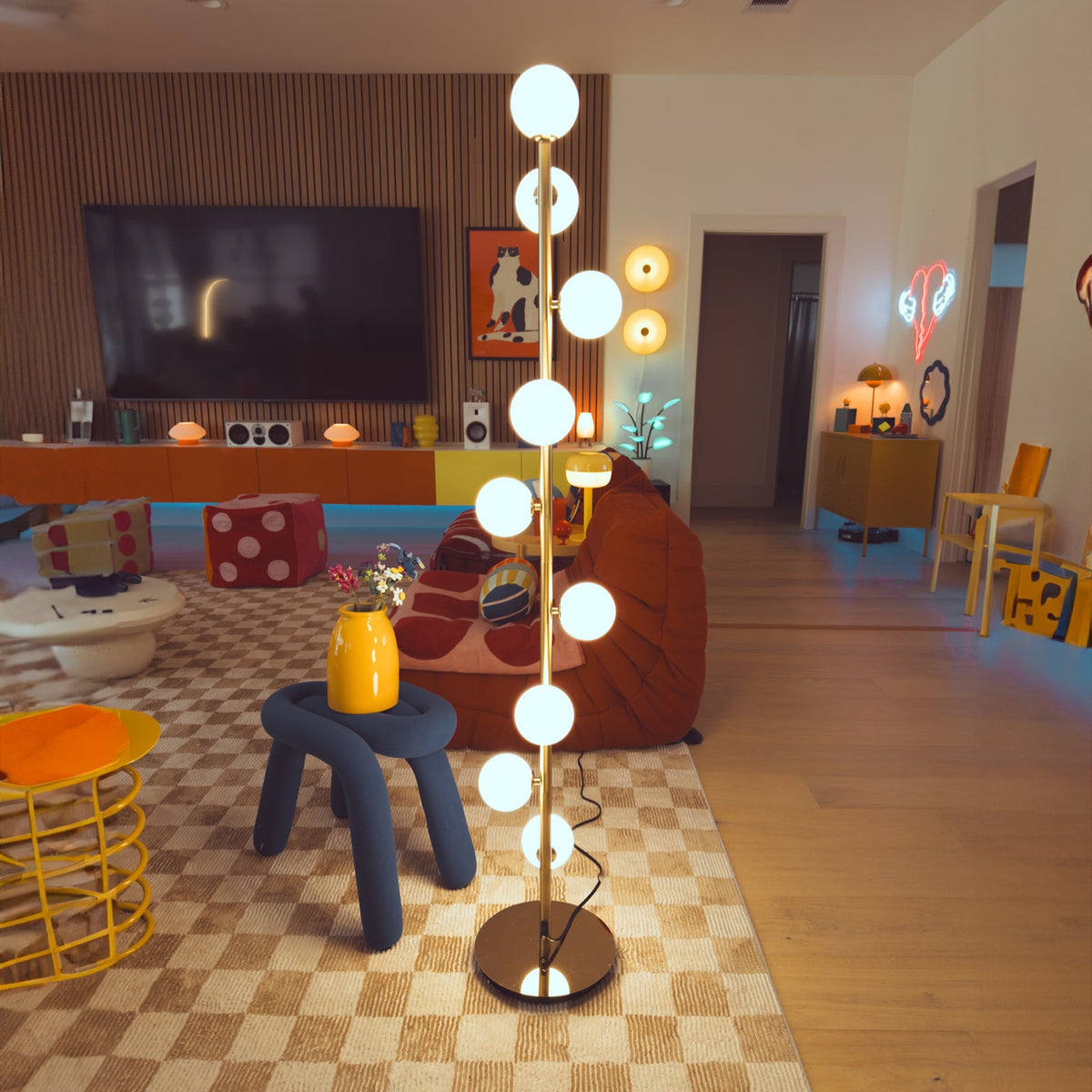 Modern living room with a decorative floor lamp, colorful furniture, and a TV.